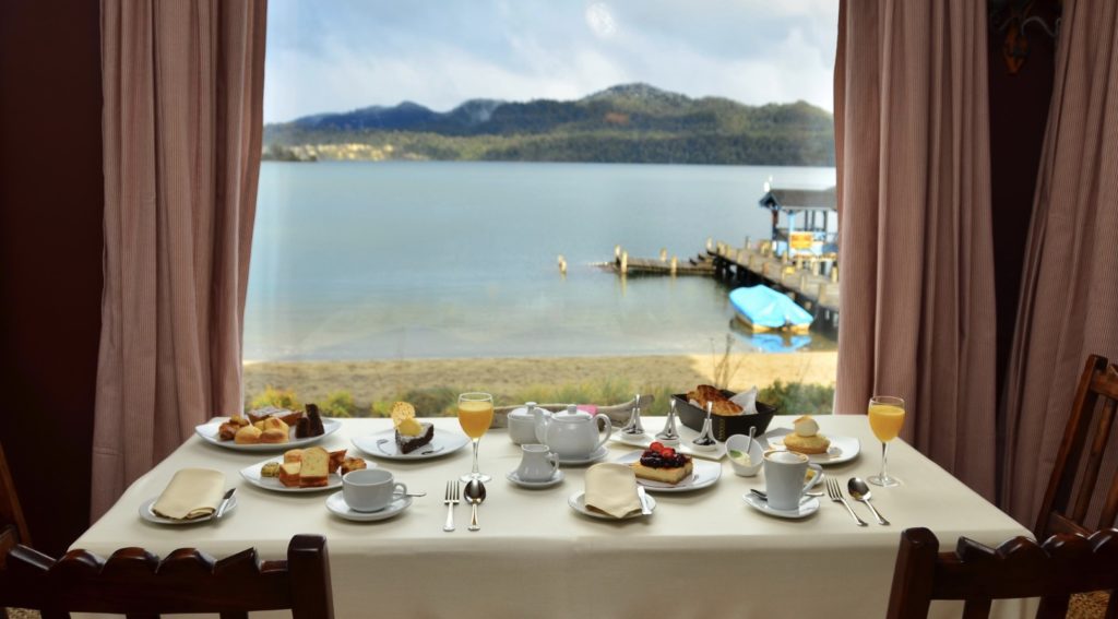 curtained window view of lake with full dining table eat in villa la angostura